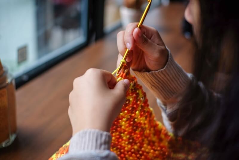 Artesã segurando duas agulhas e fazendo trico