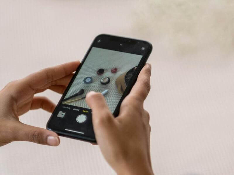 Artesão segurando o celular e fazendo foto de artesanato para divulgar suas peças