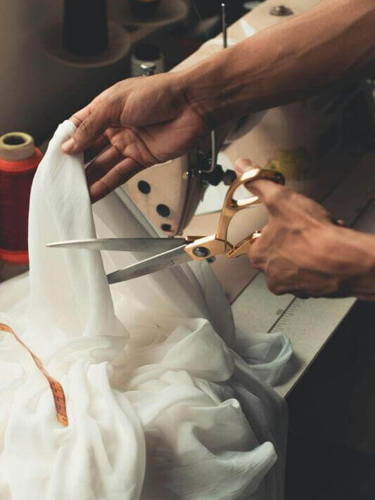 Costureira trabalhando no seu atelie cortando tecido com uma tesoura