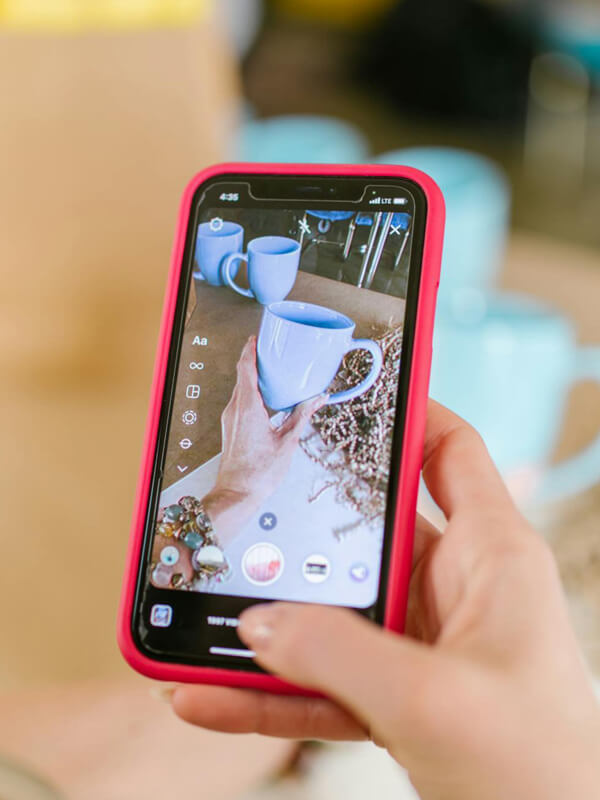 Artesã fotografando xícaras artesanais para postar no Pinterest