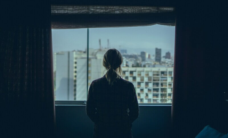 Artesã parada observando a vista de uma janela aberta