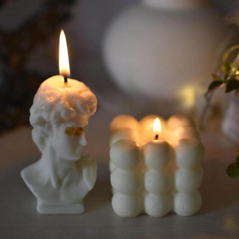 Duas velas artesanais em formatos diferentes acesas