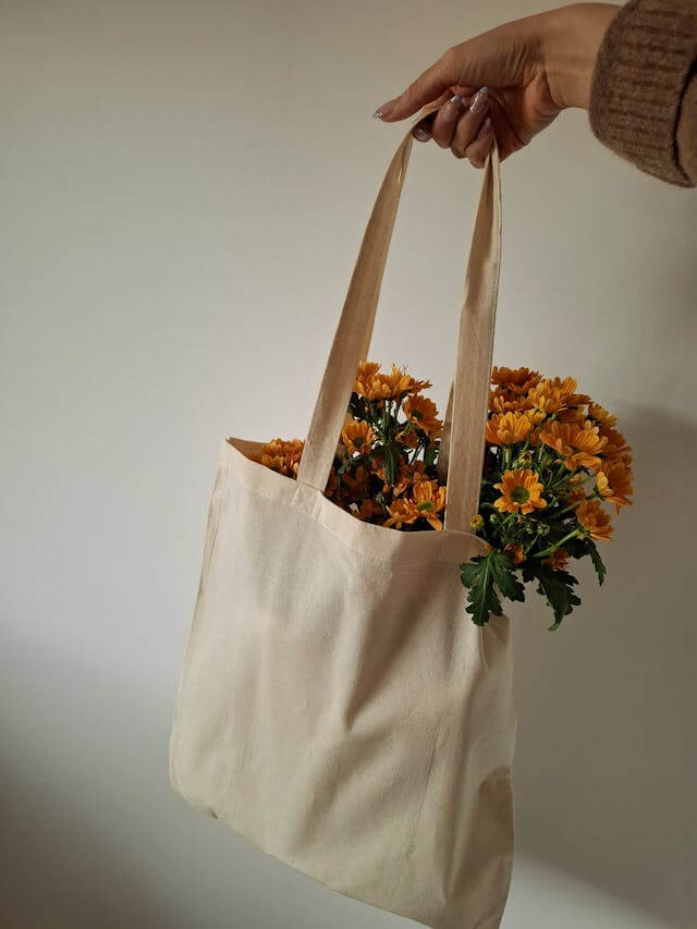artesã que fez uma ecobag com zíper segurando a bolsa que está cheia de flores